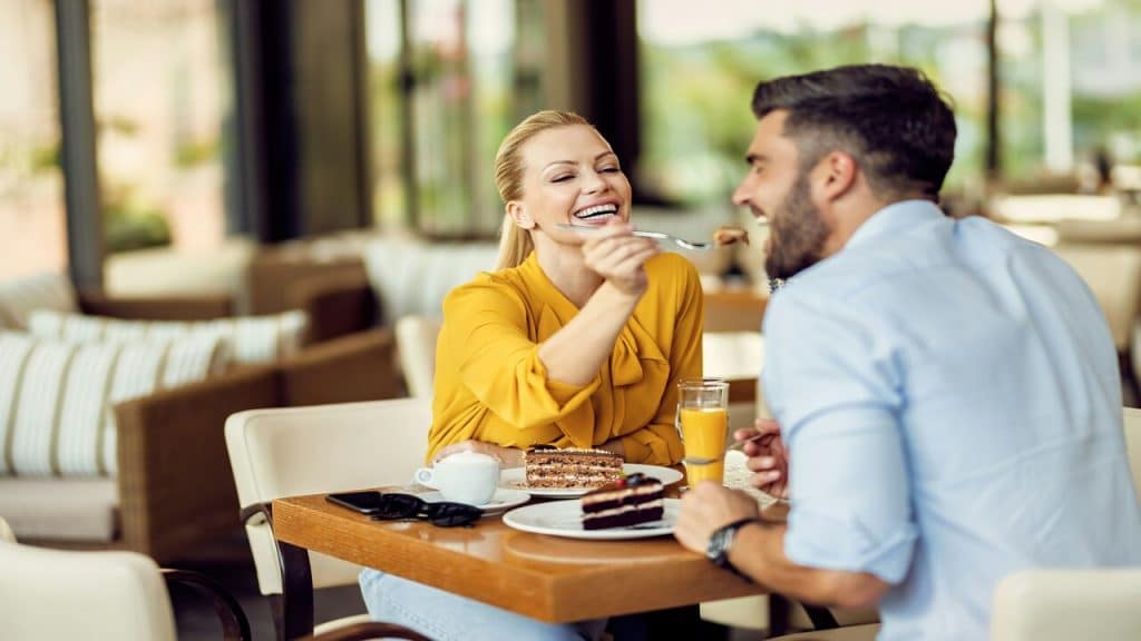 A woman feeding her husband at a cafe