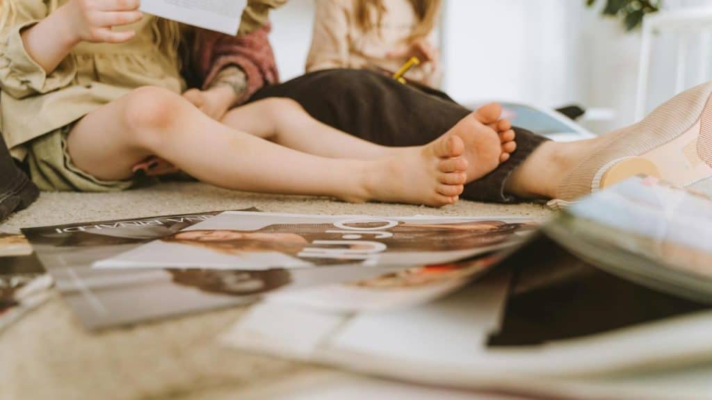 A child sitting on the floor surrounded by open magazines.
