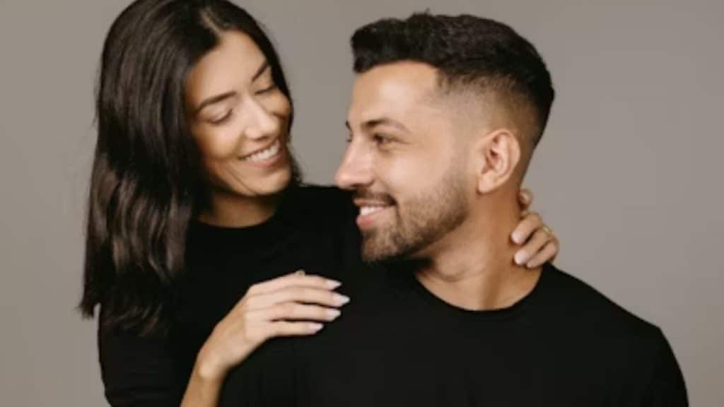 Man smiling while his partner places a reassuring hand on his shoulder