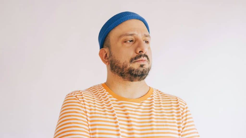 Man in a blue knit cap and orange striped shirt looking away from the camera.
