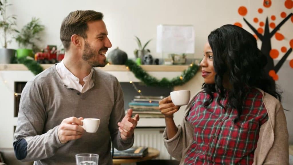 A couple having breakfast at home, a woman looking tired but smiling softly.