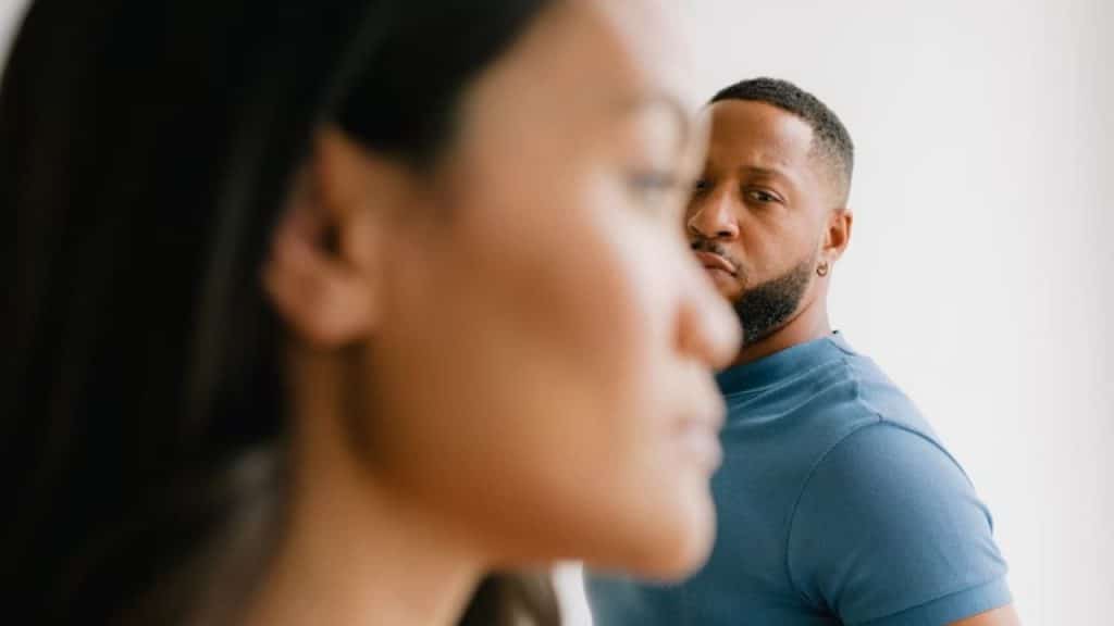 Couple in the same room, woman looking away while man glances over with concern