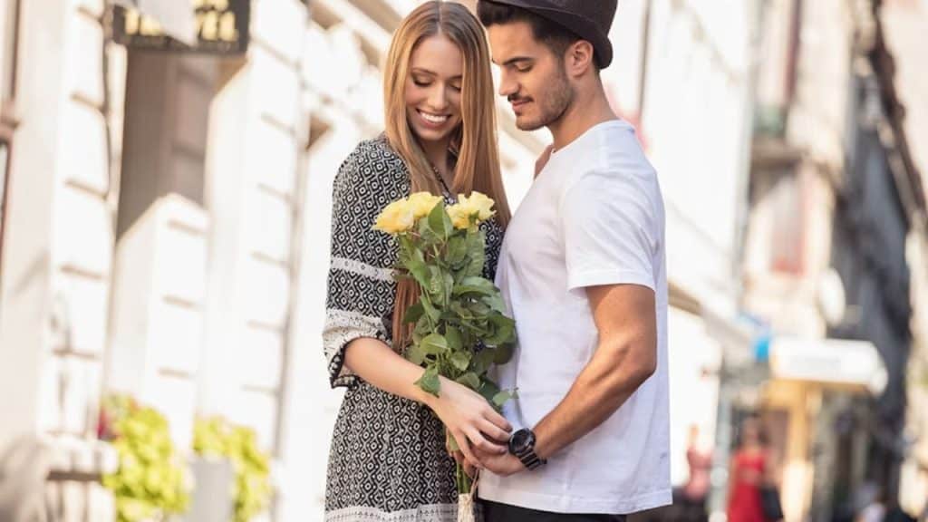 Man smiling while giving his partner flowers