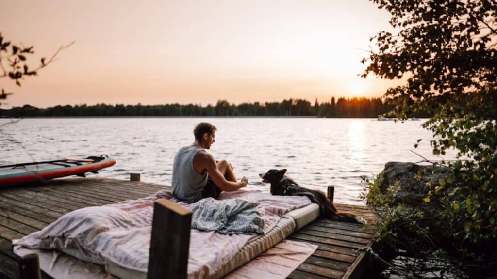Man sitting peacefully by a lake at sunset