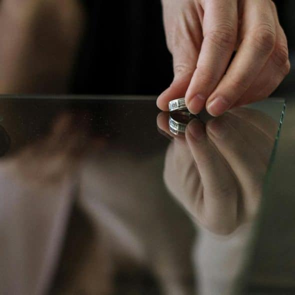 A person hand placing a silver ring