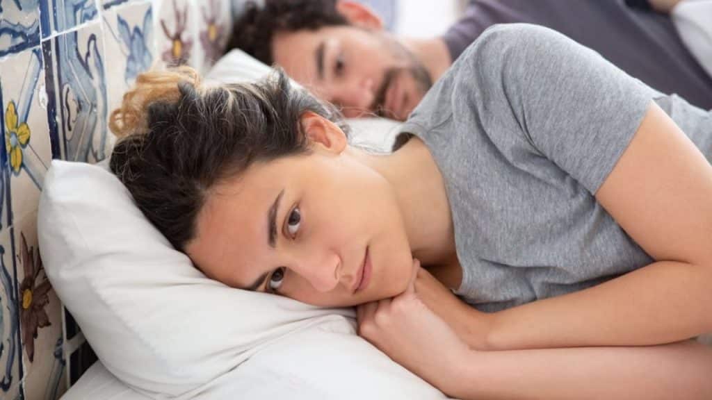 Couple sitting in bed with distant expressions