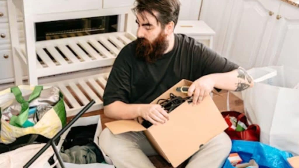 Man with messy appearance sitting casually in an unkempt living room