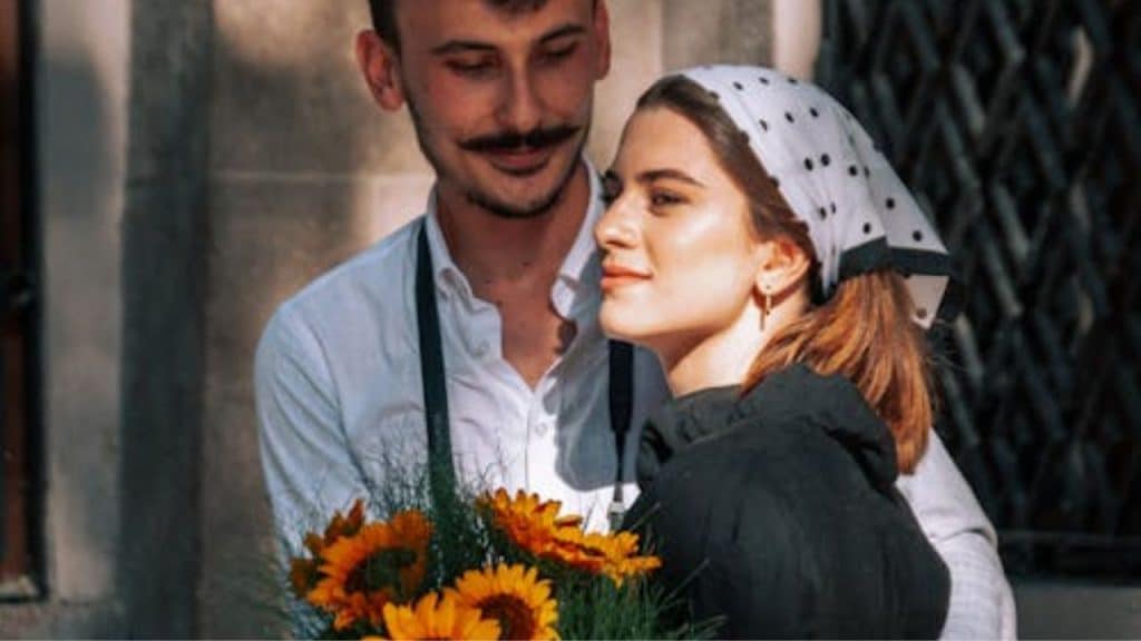 Man handing flowers to his partner while she looks distant