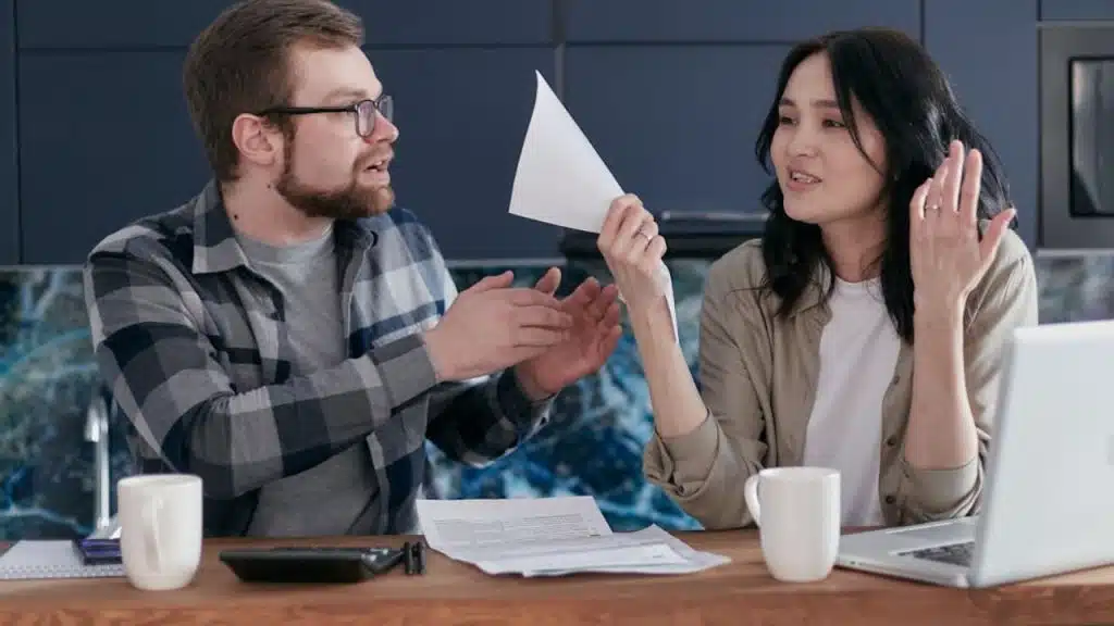 Couple reviewing finances at a table with tension visible