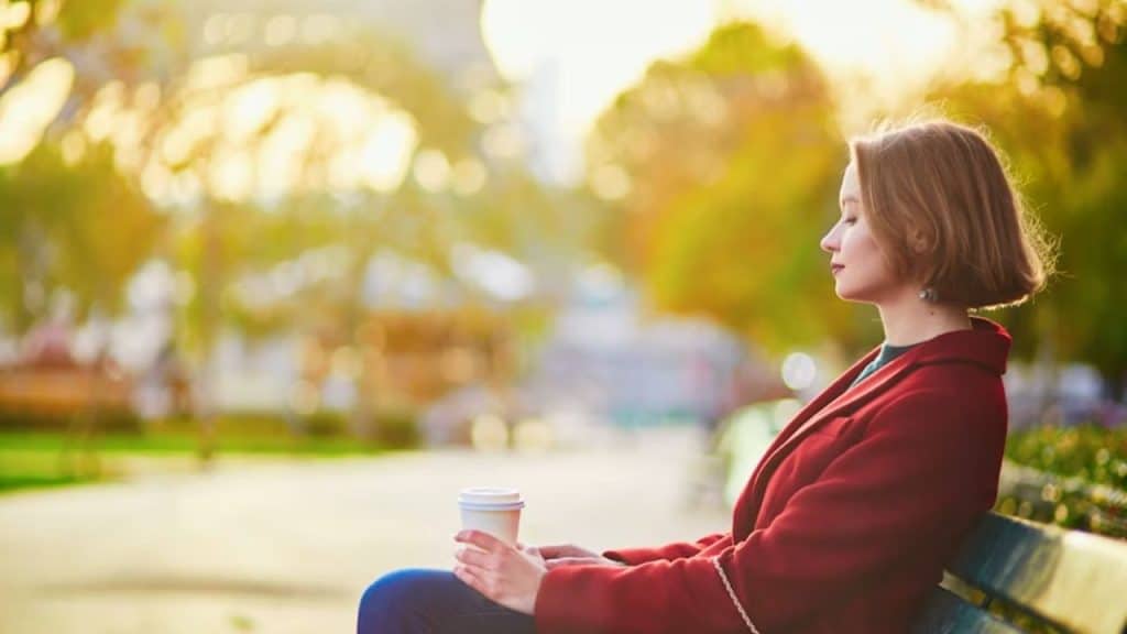 Woman sitting on a park bench alone, lost in thought