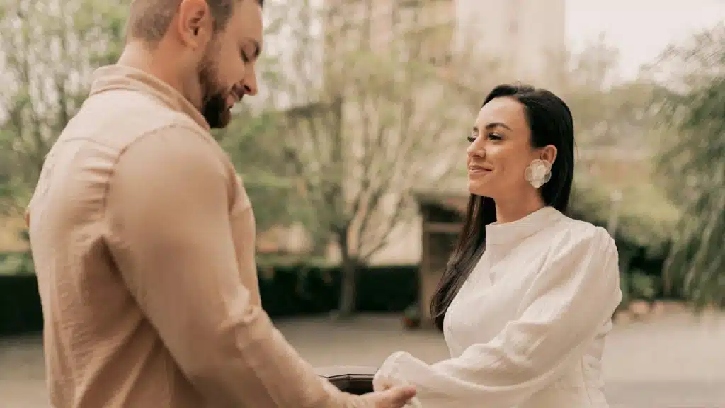 A couple holding hands while standing on a bridge.