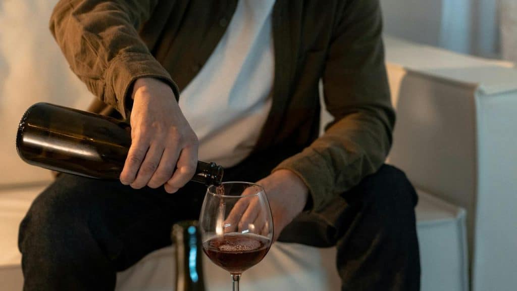 A person pouring red wine into a glass.