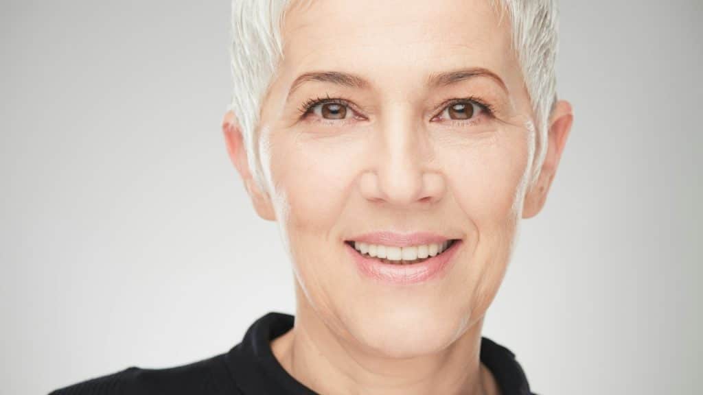 A short haired older woman smiling.