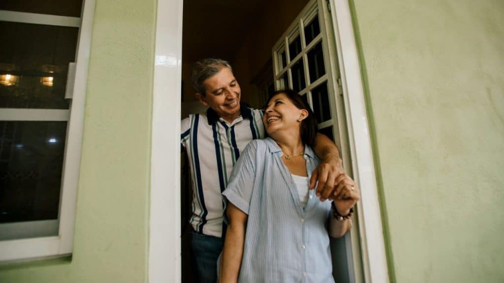 Smiling middle-aged couple standing in a doorway, looking at each other.