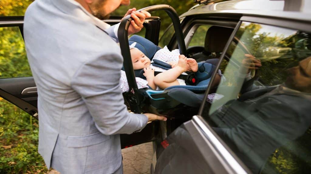 A man putting his baby in the car
