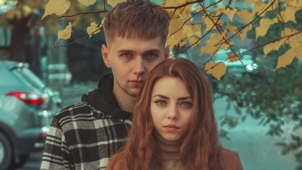A man and a woman standing under a tree.