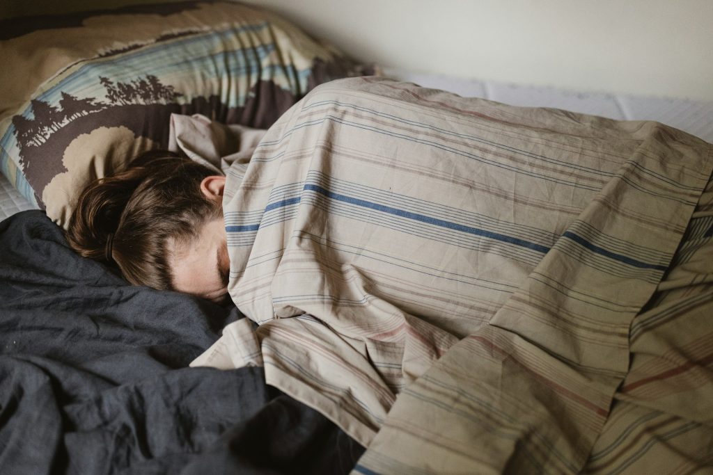 The woman is sleeping under the blanket.
