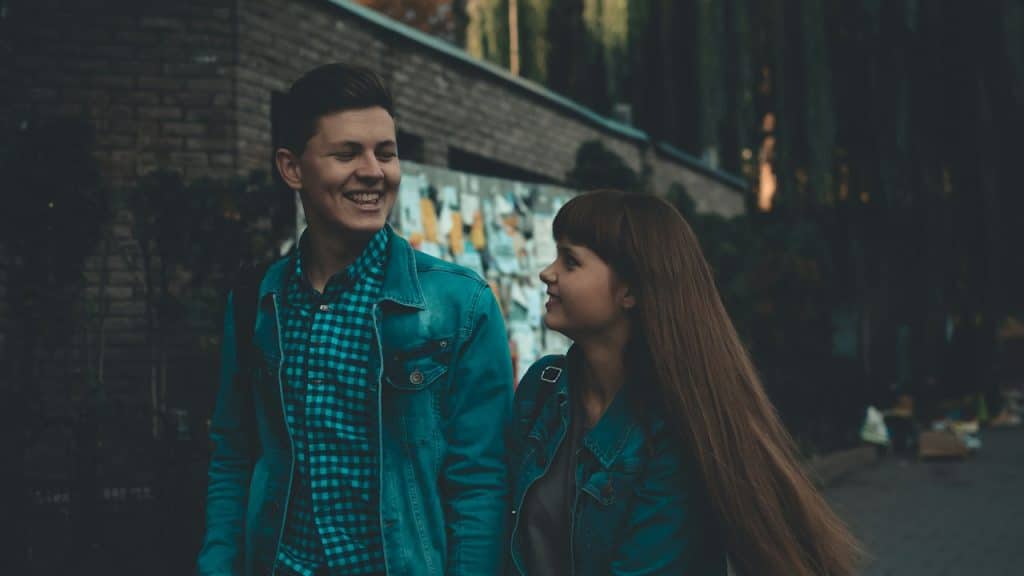A smiling couple walking down a street on a date.