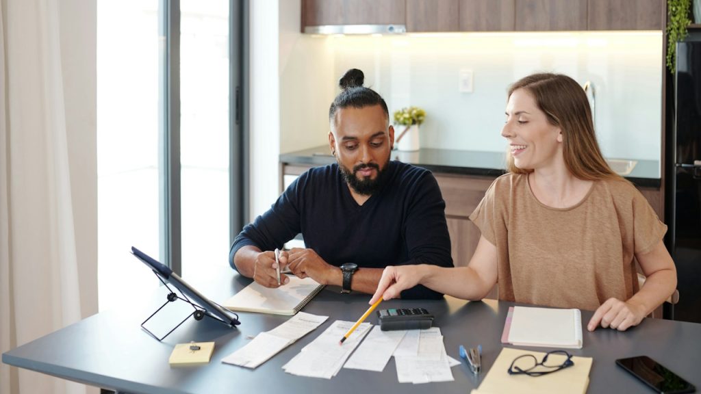 A couple discussing monthly expenditure and savings at home.