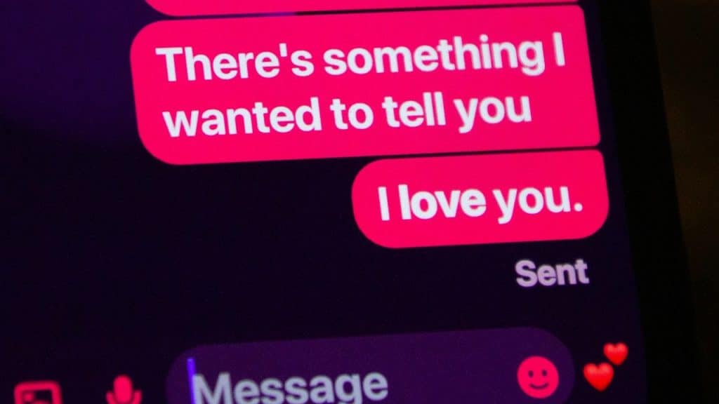 Close-up of a smartphone screen showing a dark-mode text conversation with bright pink bubbles.