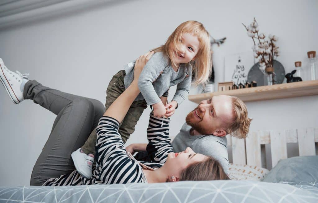 The parents are playing with their daughter.