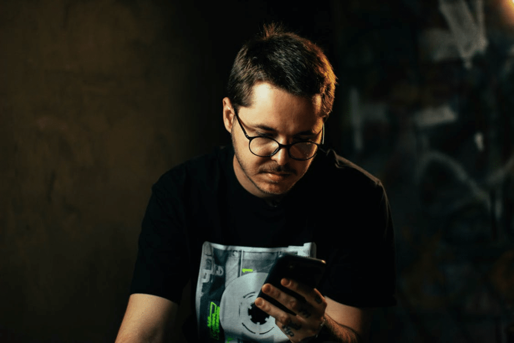 Man in Black Crew Neck Shirt Busy Using His Cellphone