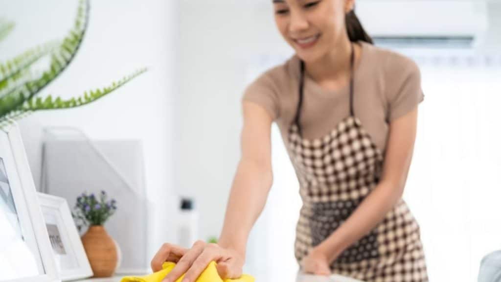 A woman smiling politely while juggling multiple household tasks