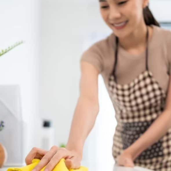 A woman smiling politely while juggling multiple household tasks