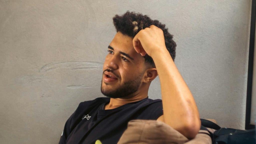 A man sitting on a couch with his hand on his head looking thoughtful.