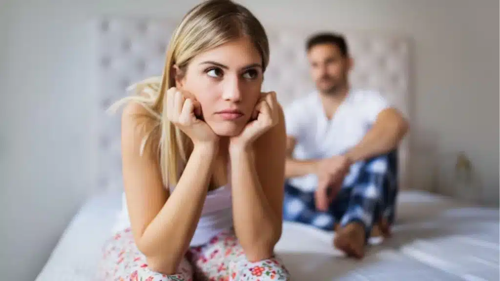 Woman sitting quietly on the couch while her partner looks away
