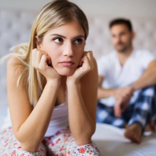 Woman sitting quietly on the couch while her partner looks away