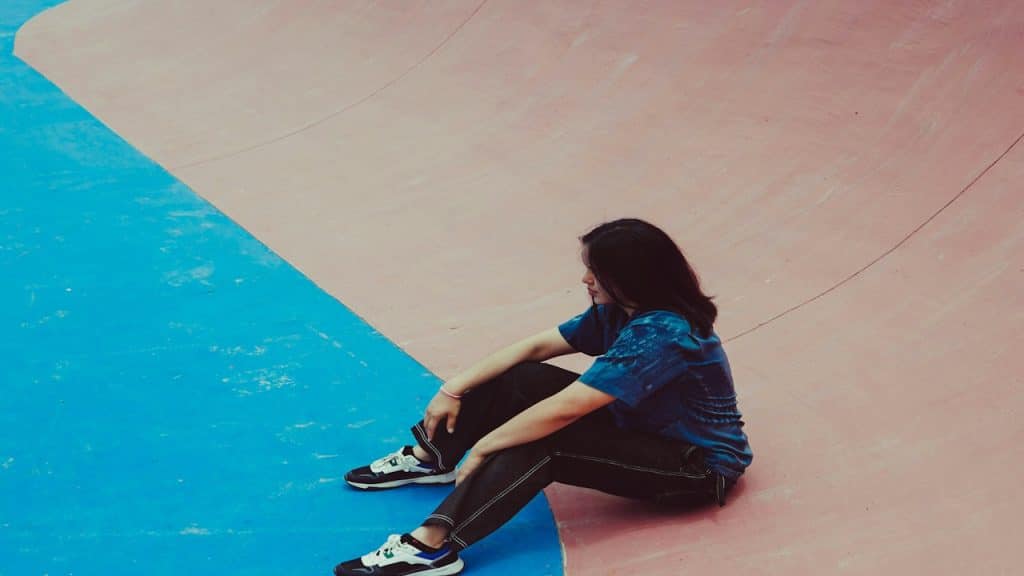 A woman sitting silently in a skate park.