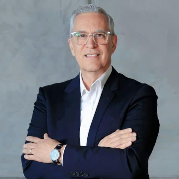 Middle-aged man in a dark suit and glasses with arms crossed.