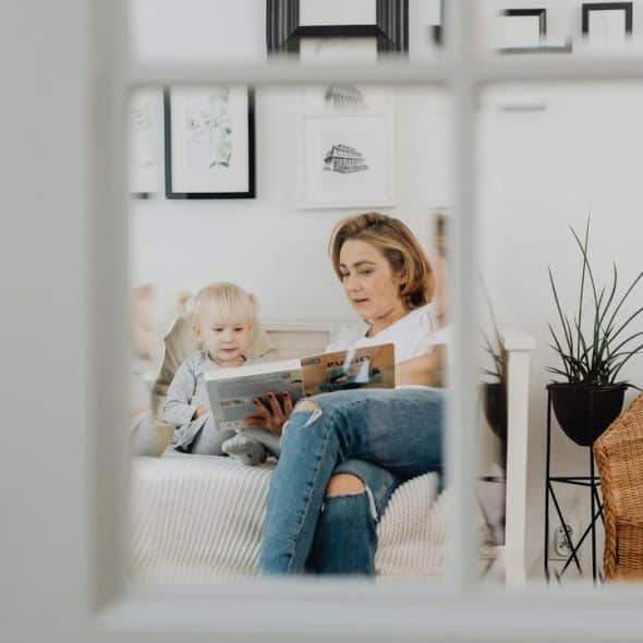 A woman reading a book to a young child in a cozy living room.