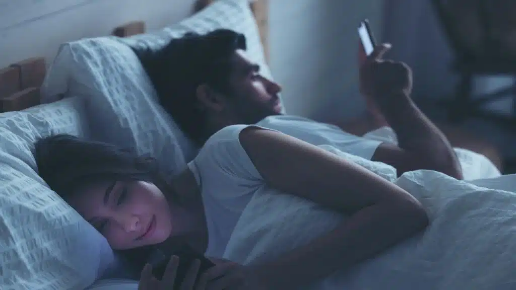 A couple busy with their phones in bed