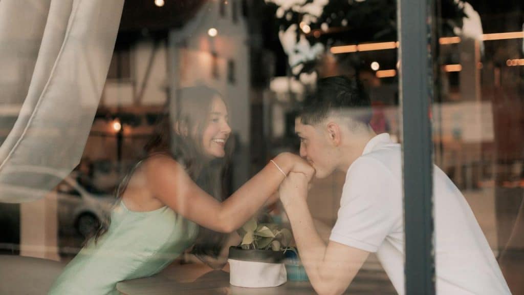 A couple smiling and holding hands across a table in a cozy café.