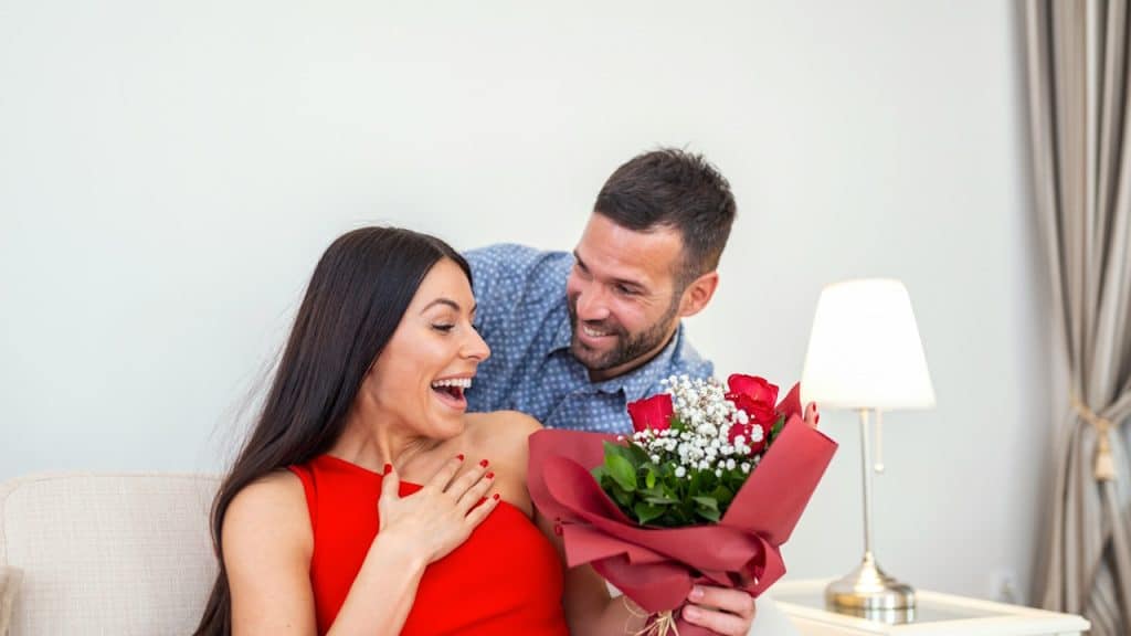 A woman receiving an unexpected bouquet of red roses from her husband.