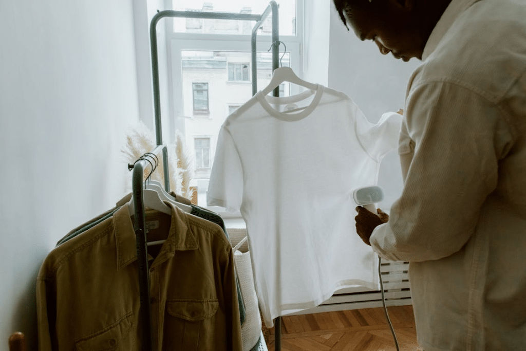 Man Steam Ironing Shirt Hanging from Clothing Rack