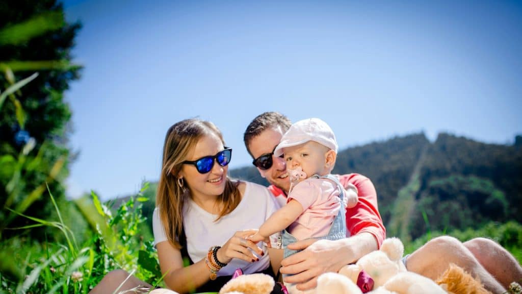 A lovely couple carrying a small baby.