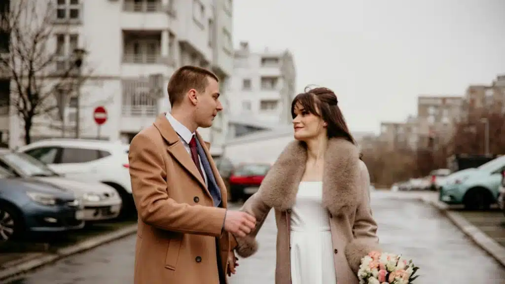 A man and a woman holding hands on a city street.