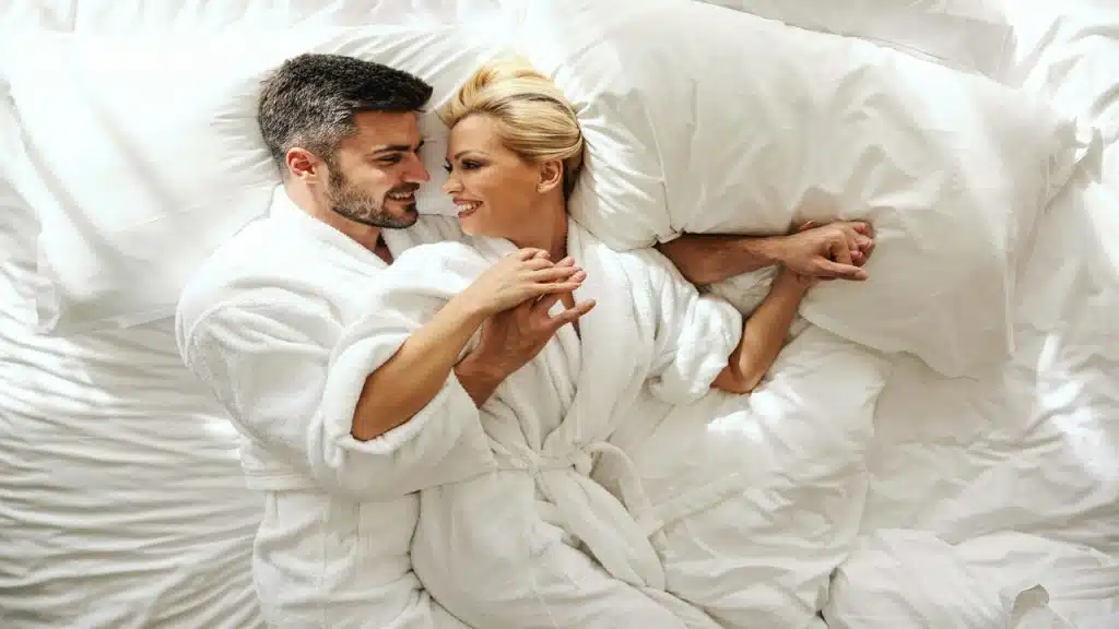 A couple smiling at each other in bed