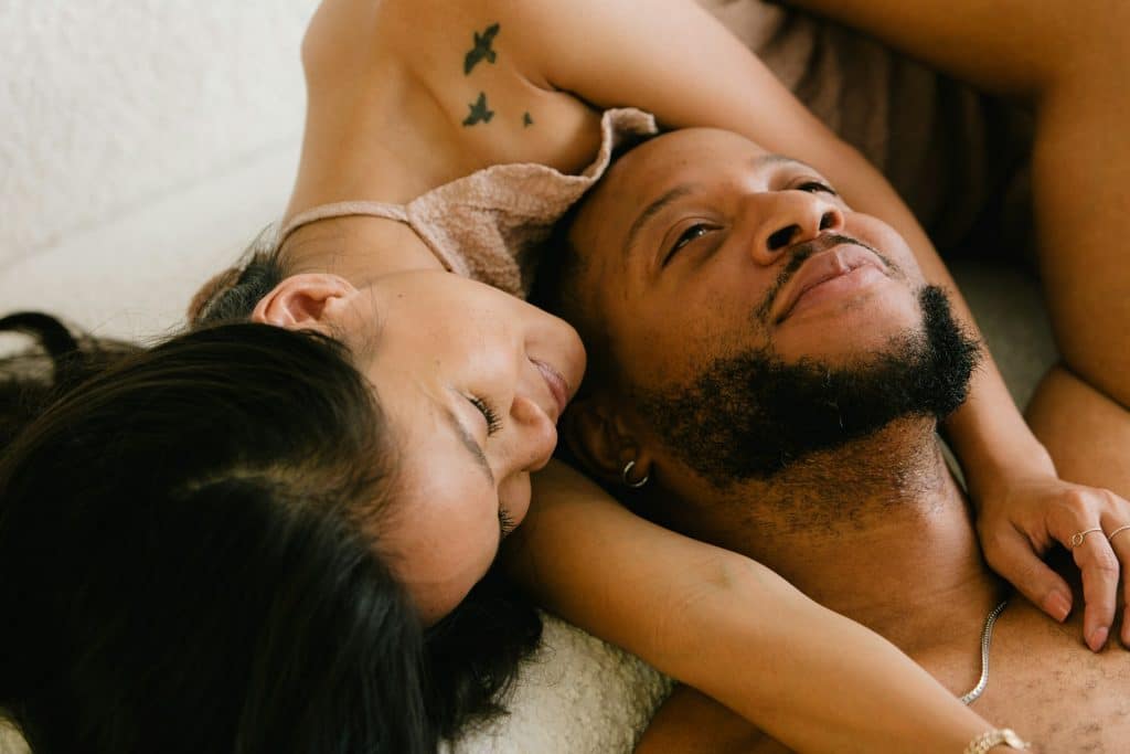 The couple is lying on the bed together.