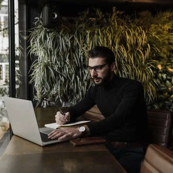 A Man using Laptop while Writing