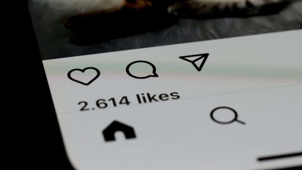 Close-up on a smartphone screen showing social media engagement icons and "2,614 likes" below a cropped photo.