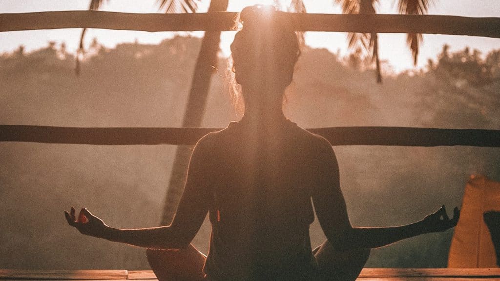 A woman doing yoga meditation on brown parquet flooring.