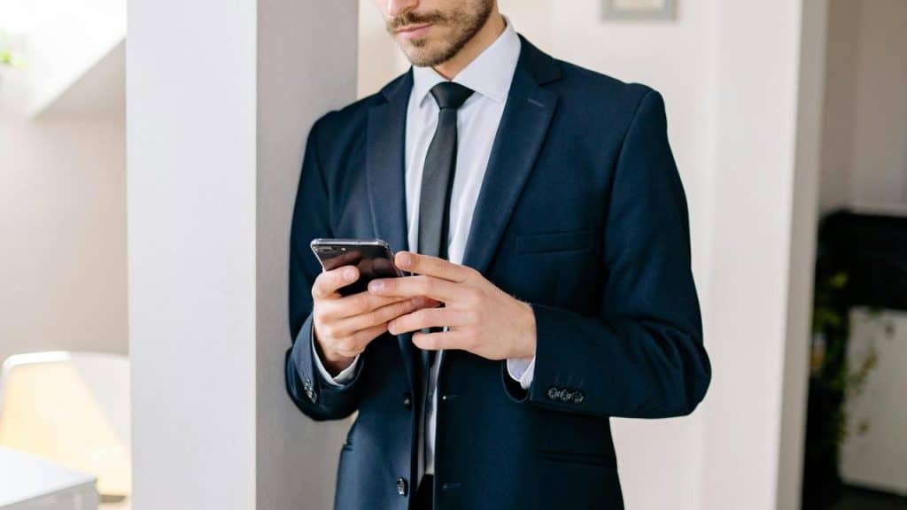 A man in a suit using a smartphone indoors.