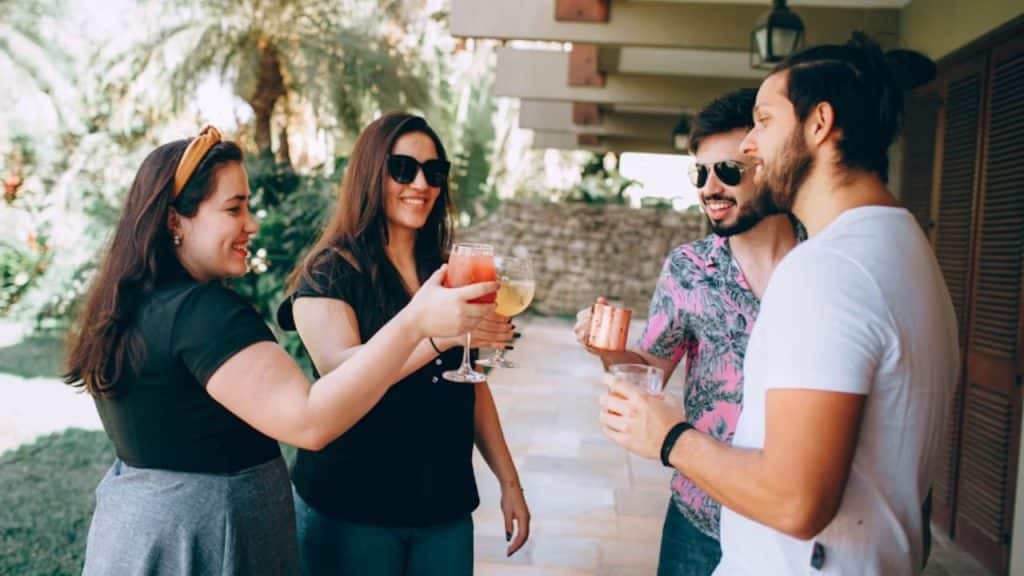 A couple at a social gathering, woman laughing as her friends tease her boyfriend