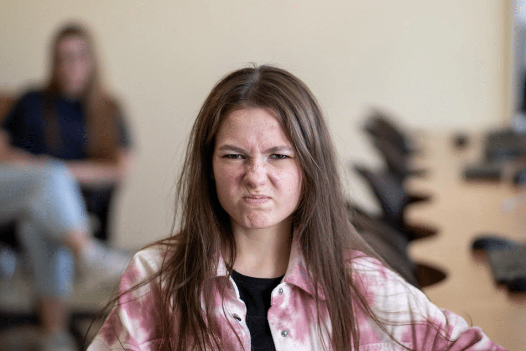 Angry Girl Sitting at Desk in Classroom