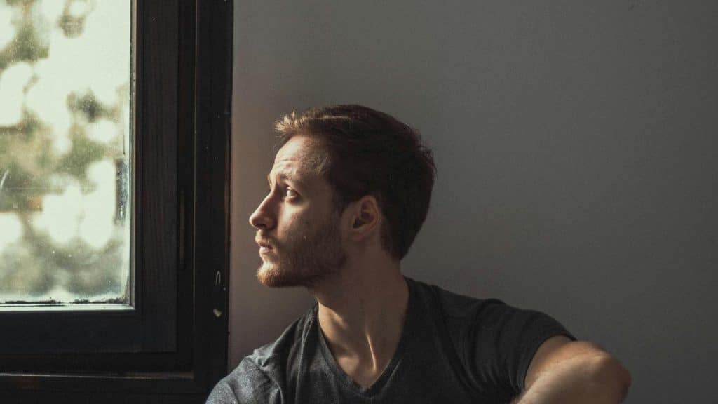 A man sitting by a window looking outside.