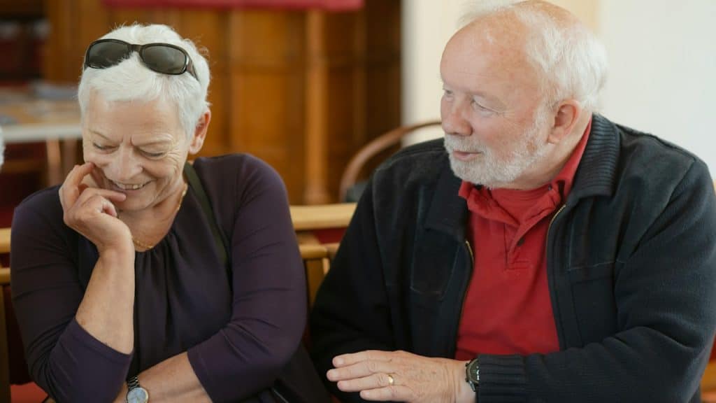 An older couple talking and smiling indoors.